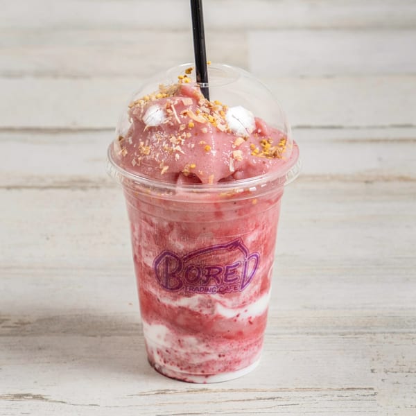 A pink smoothie with white swirls, topped with granola and bee pollen, from Bored Trading Cafe.